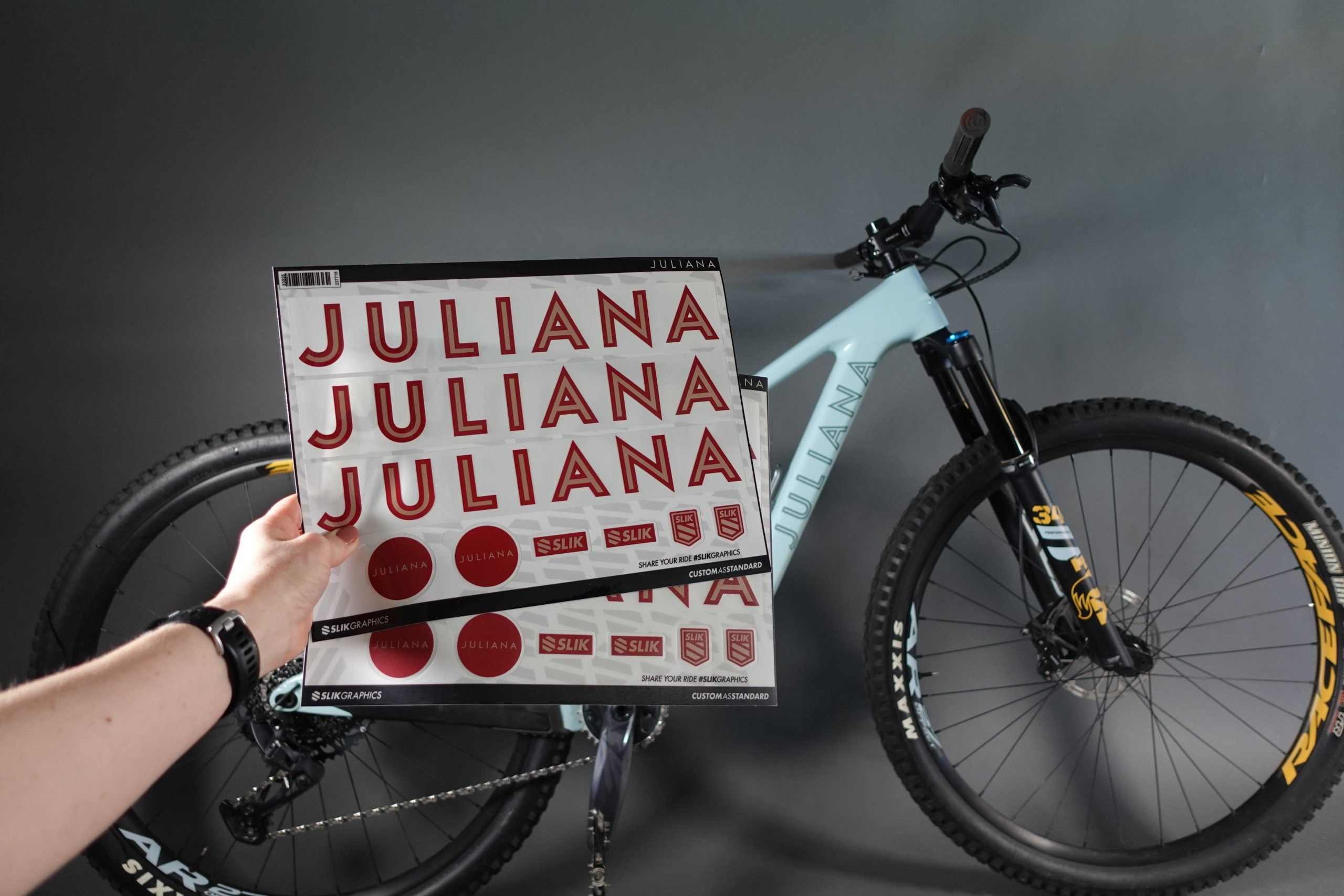 Decals sheets with matte and transparent application film. Hand holding the decal sheets in front of a Juliana mountainbike.